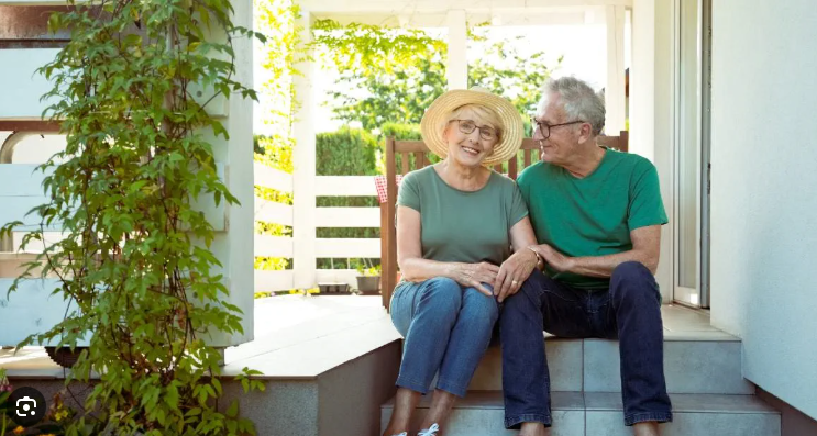 Smiling homeowners sitting together on the front steps of their house